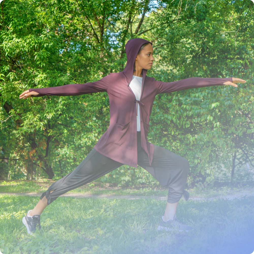 A female doing yoga outdoor in a burgundy Move It Cardigan and a black Swift Wide-Leg Sweatpant, both modest activewear garments from Veil Garments.