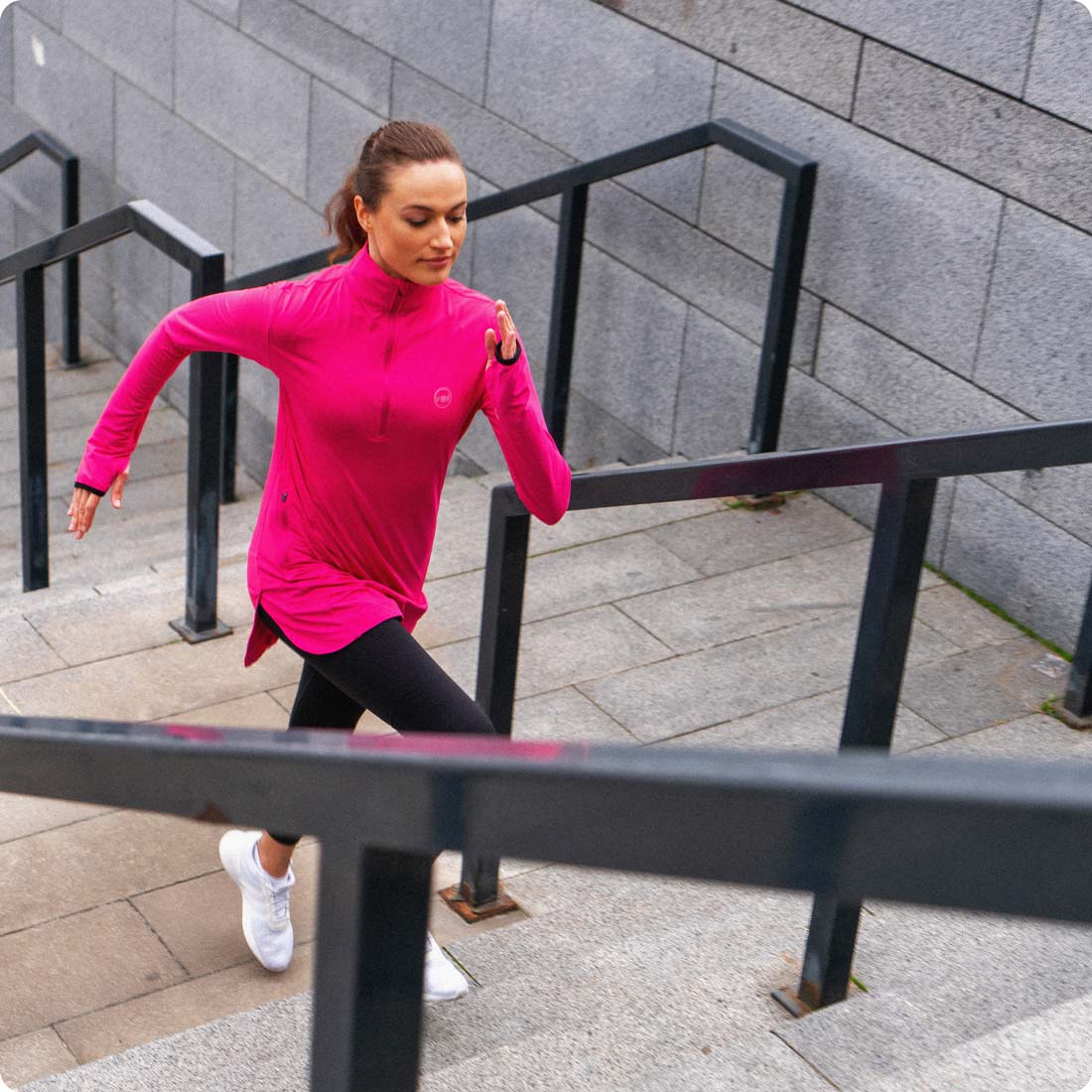 A female running outdoor in a pink Spark Half-Zip, a modest activewear sweatshirt from Veil Garments.