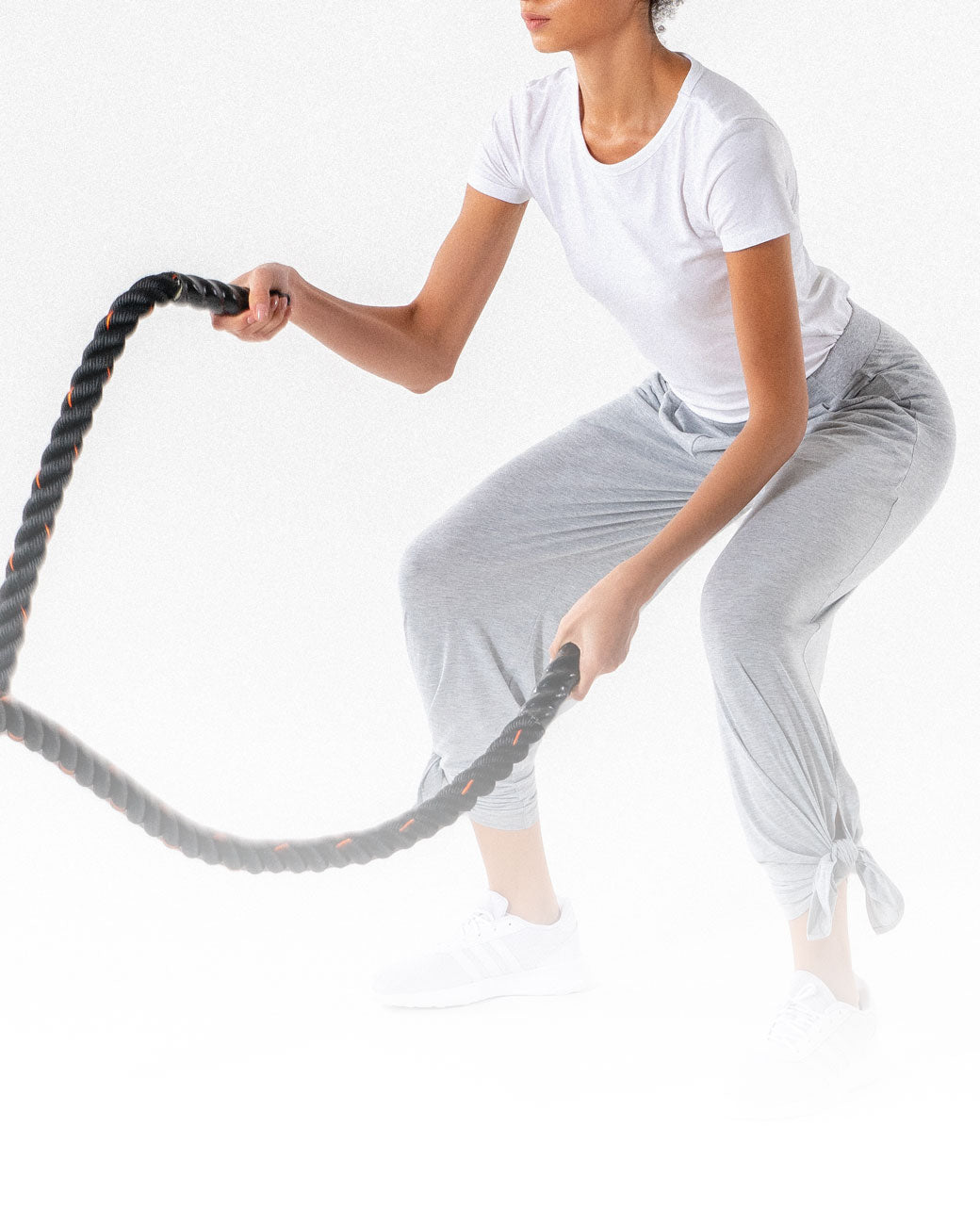 A female exercising with ropes while wearing a light grey Swift Wide-Leg Sweatpant, a modest activewear sweatpant from Veil Garments.