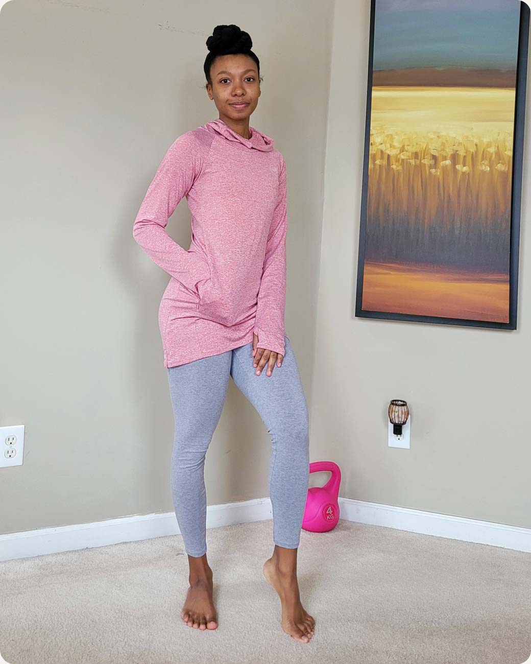 A customer smiling and posting in the red Halo Running Hoodie, a modest sportswear sweatshirt from Veil Garments.