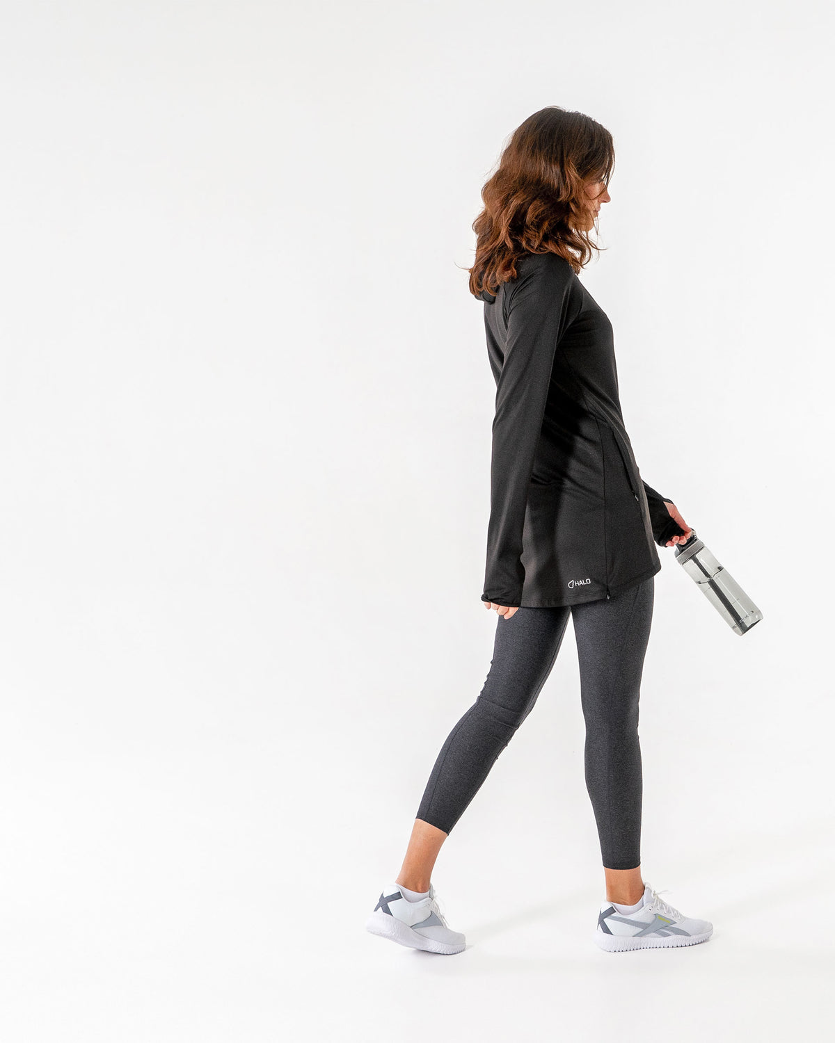 Black Halo Running Hoodie seen in profile over grey leggings, hood down and a water bottle in hand.

#color_black