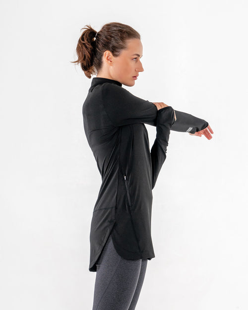 Spark Half-Zip in black from the side, one arm stretched across with the thumbhole cuff in view.

#color_black
