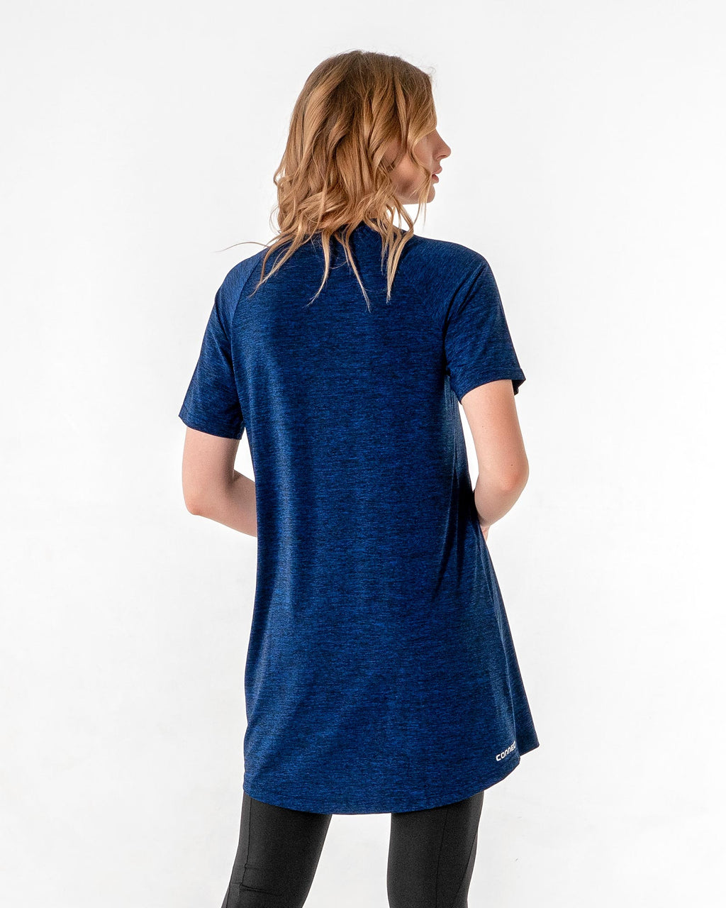 Back of the Connect T-Shirt Dress in Blue/Black, showing the curved hem over black leggings.

#color_blue-black