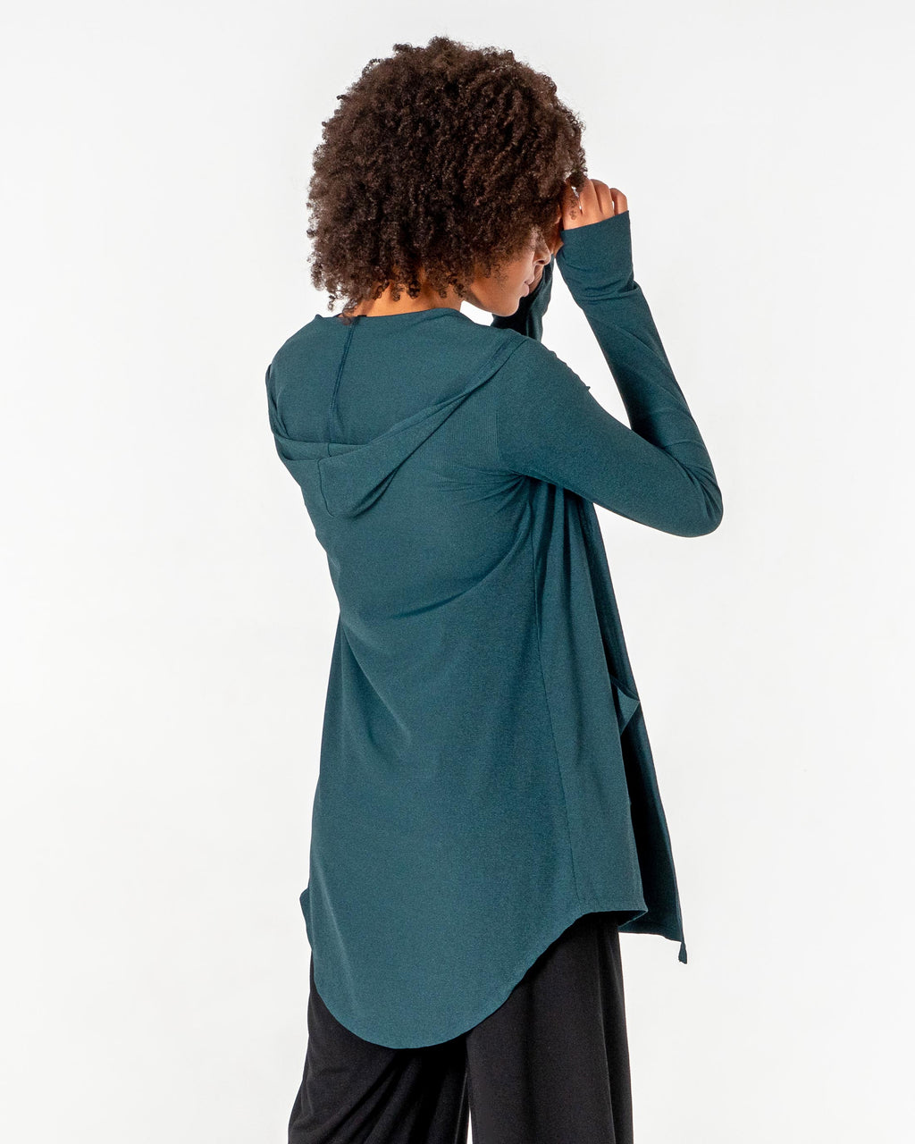 Back view of the emerald green Move It Cardigan with one arm raised, showing the curved hem.

#color_emerald-green