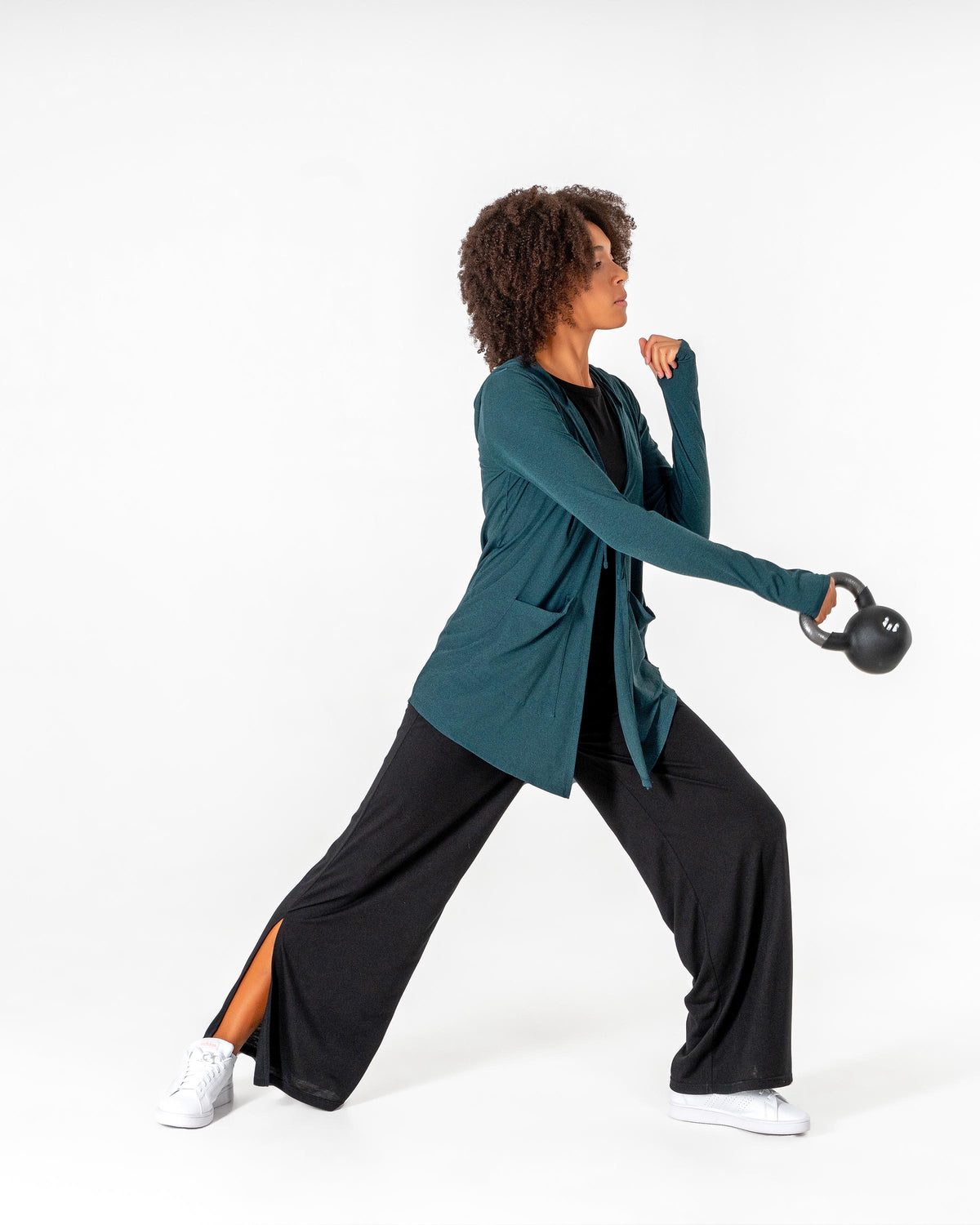 Emerald green Move It Cardigan on a model in a lunge holding a kettlebell, worn over black pants.

#color_emerald-green